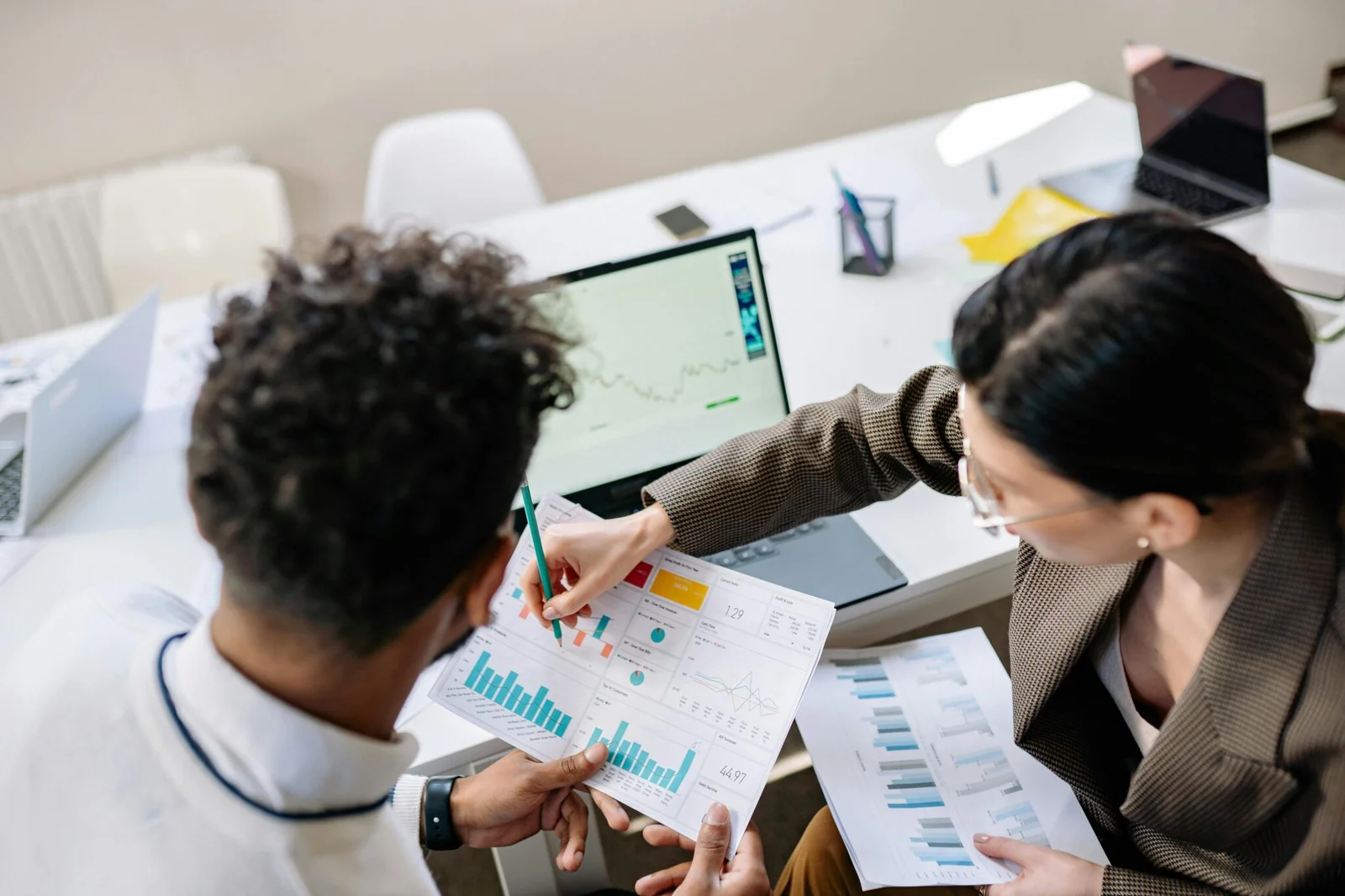 Two marketing consultants reviewing analytics charts and data visualizations during a strategy meeting