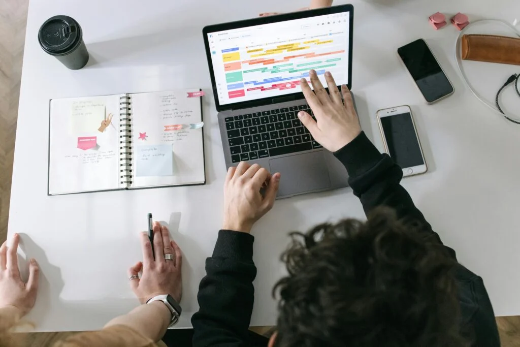 Professional team working on employer branding strategy with laptop displaying colorful project timeline and planning materials