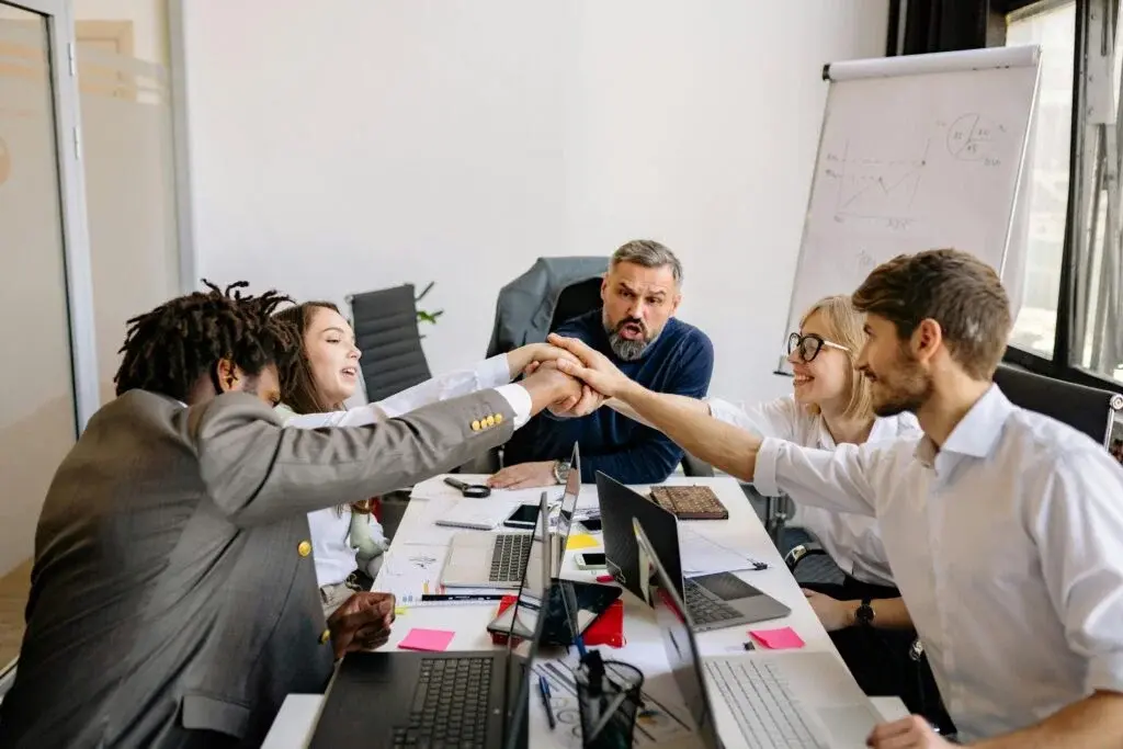 Pearl Lemon Consulting Canada executive team collaboration meeting with diverse professionals doing team handstack in modern boardroom