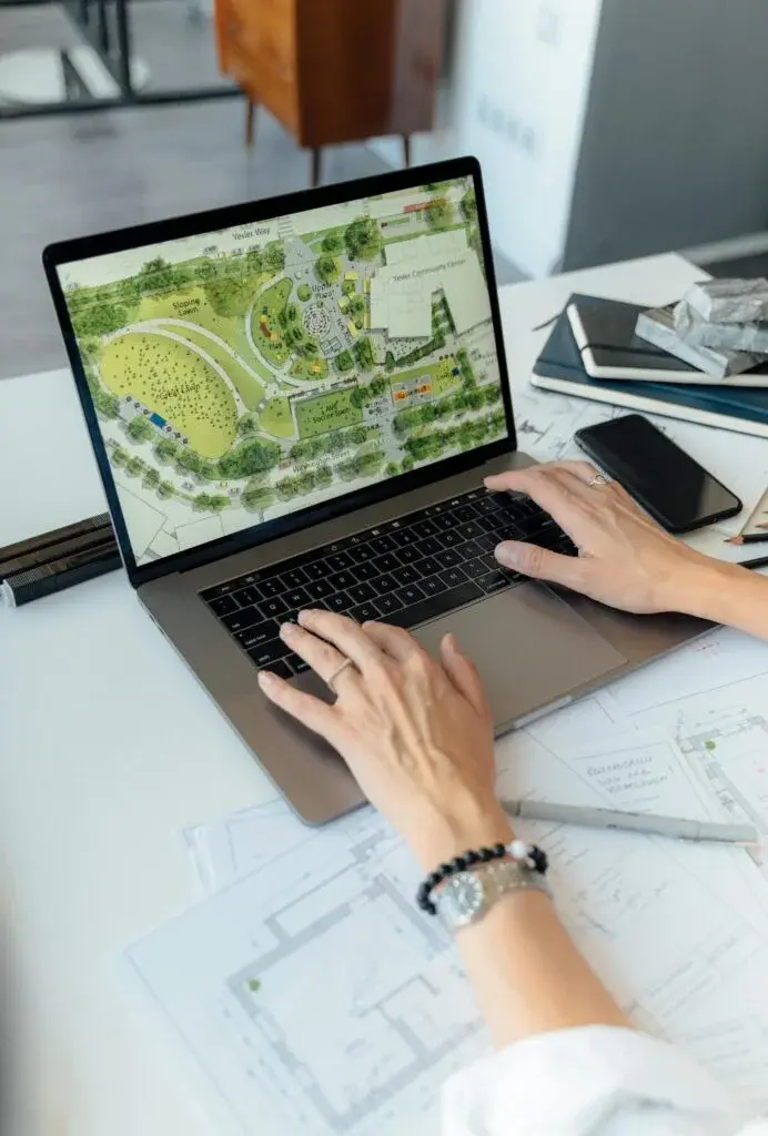 Professional working on laptop displaying organizational development and team planning layouts with documents