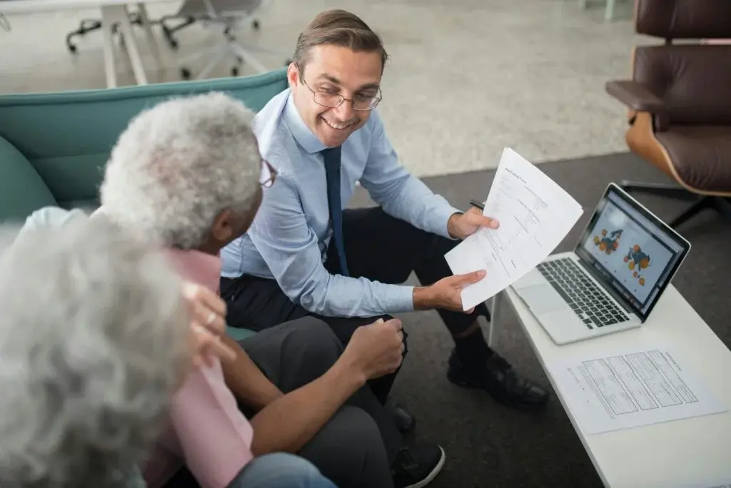 Business consultant presenting strategic planning documents to senior client in modern office setting