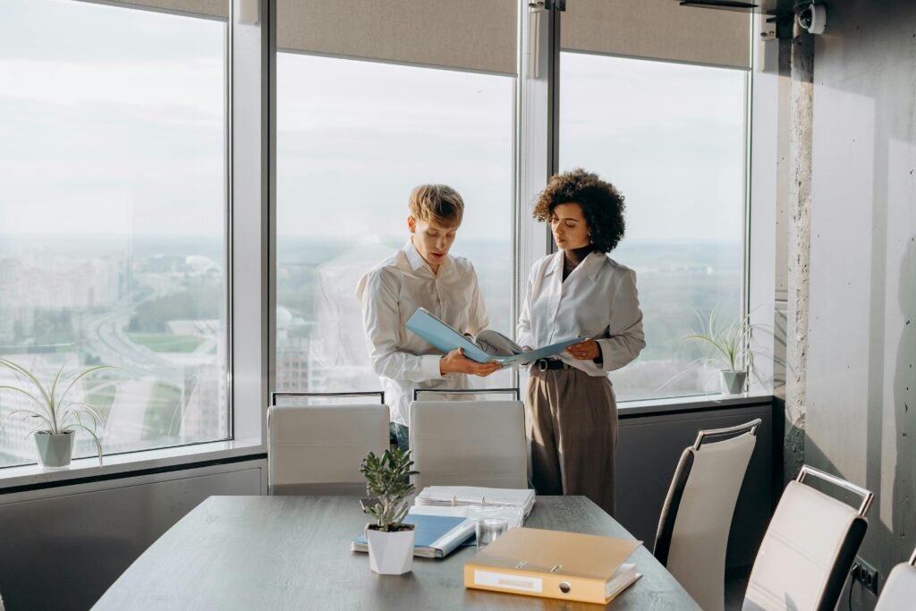 Two sustainability consultants reviewing environmental reports and ESG documentation in modern office for Canadian business clients