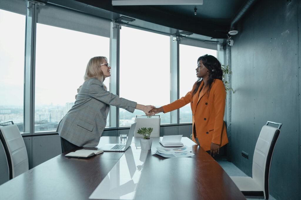 Two professionals shaking hands in a business setting after a successful meeting.