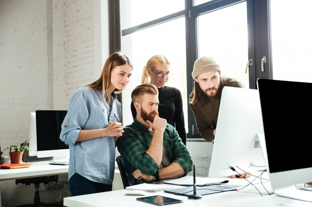 Four professionals reviewing computer at desktop